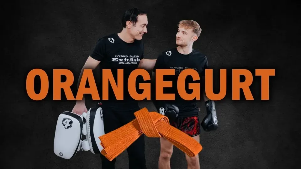 Cover Orangegurt: zwei Trainer mit Pratzen hinter einem orangen Gürtel