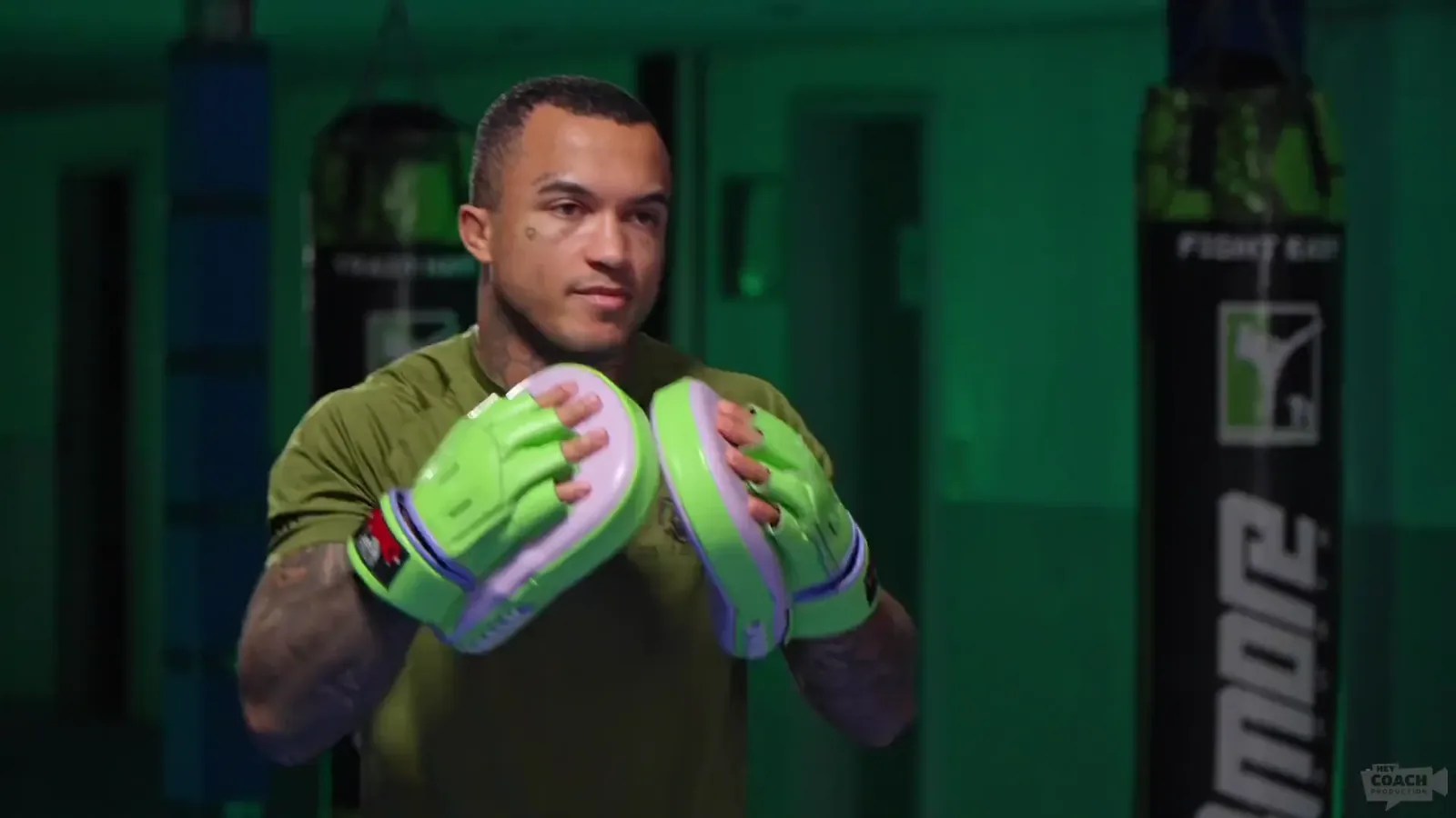 Marlon Tröscher mit Pratzen im grün beleuchteten Gym — Standbild aus dem Hero-Video von heycoachproduction.de, gedreht von Leo