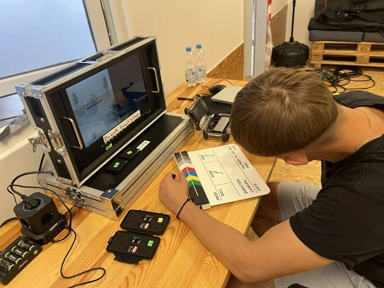 Vor dem ersten Take: Filmklappe, Vorschaumonitor und Speicherkarten auf dem Tisch, eine Hand an der Klappe